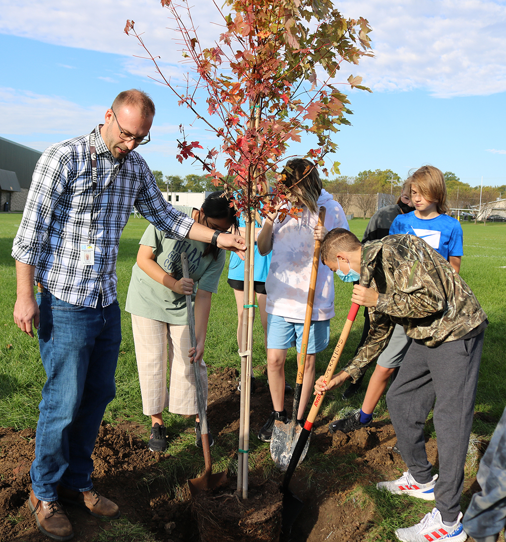 group of adults and children planting a tree